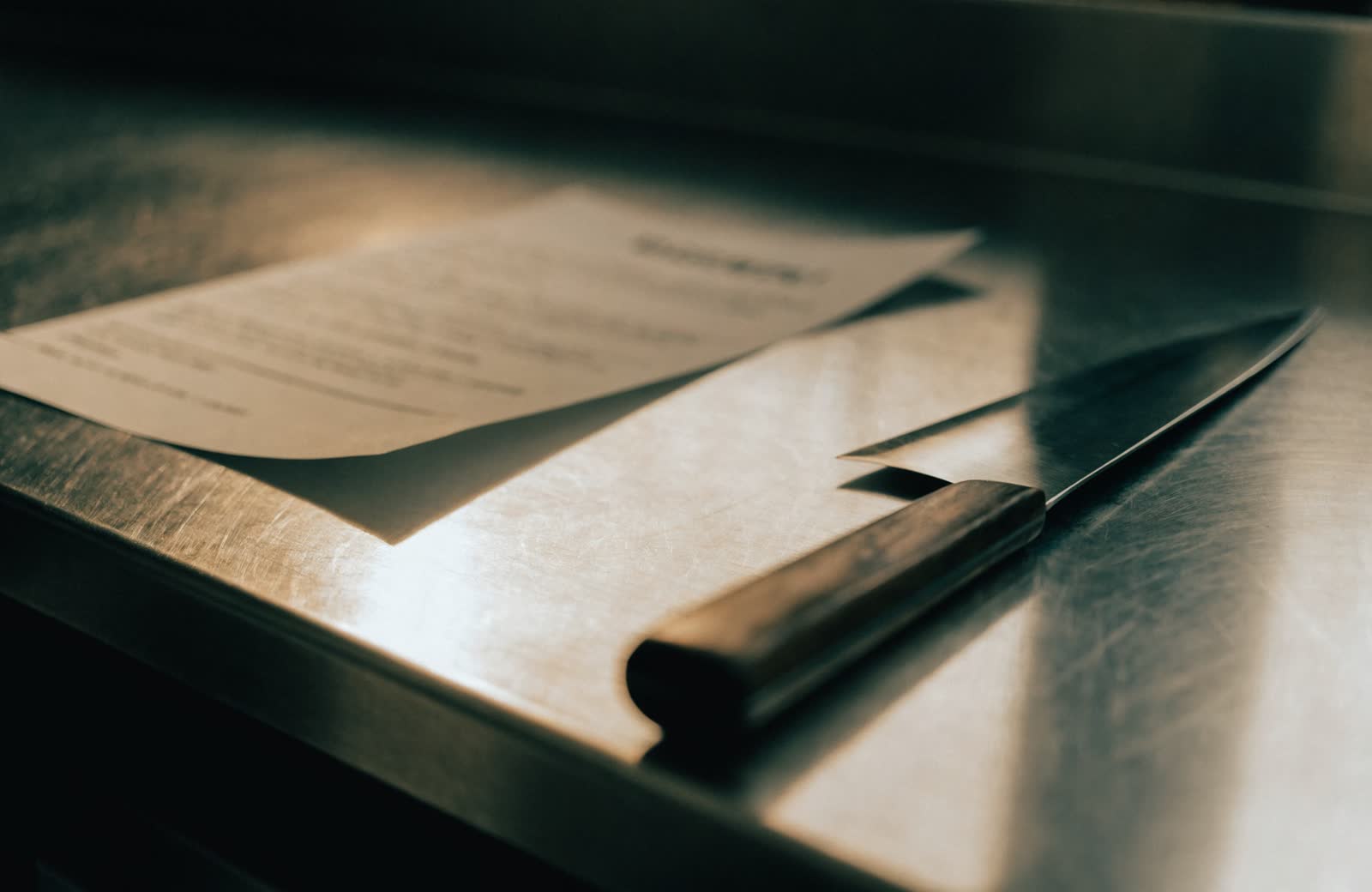 Un documento di trasporto appoggiato su un piano di acciaio accanto a un coltello da cuoco