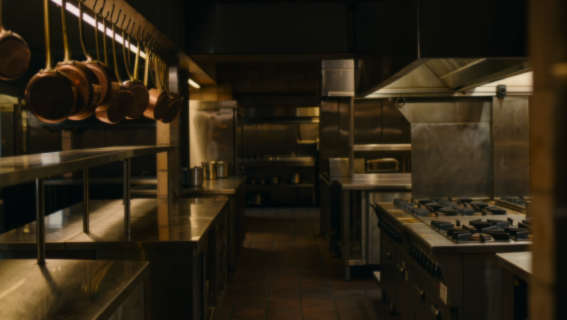 Una cucina professionale vuota, acciaio e rame, luce calda della sera